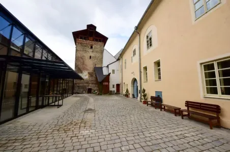 Historická věž a nádvoří v Litomyšli s kamennou dlažbou.