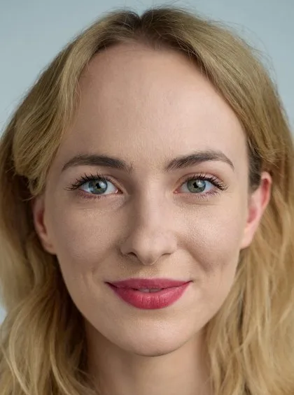 Portrét ženy s blond vlasy, která se usmívá.