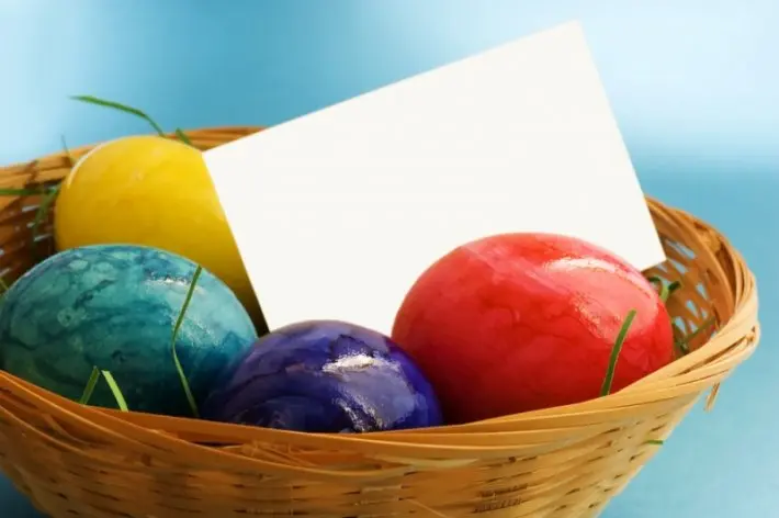 Koš s barevnými velikonočními vajíčky a prázdnou kartičkou.