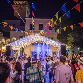 Venkovní koncert na scéně s diváky za večera.
