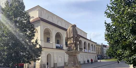 Historická budova s sochou na náměstí v Prostějově.