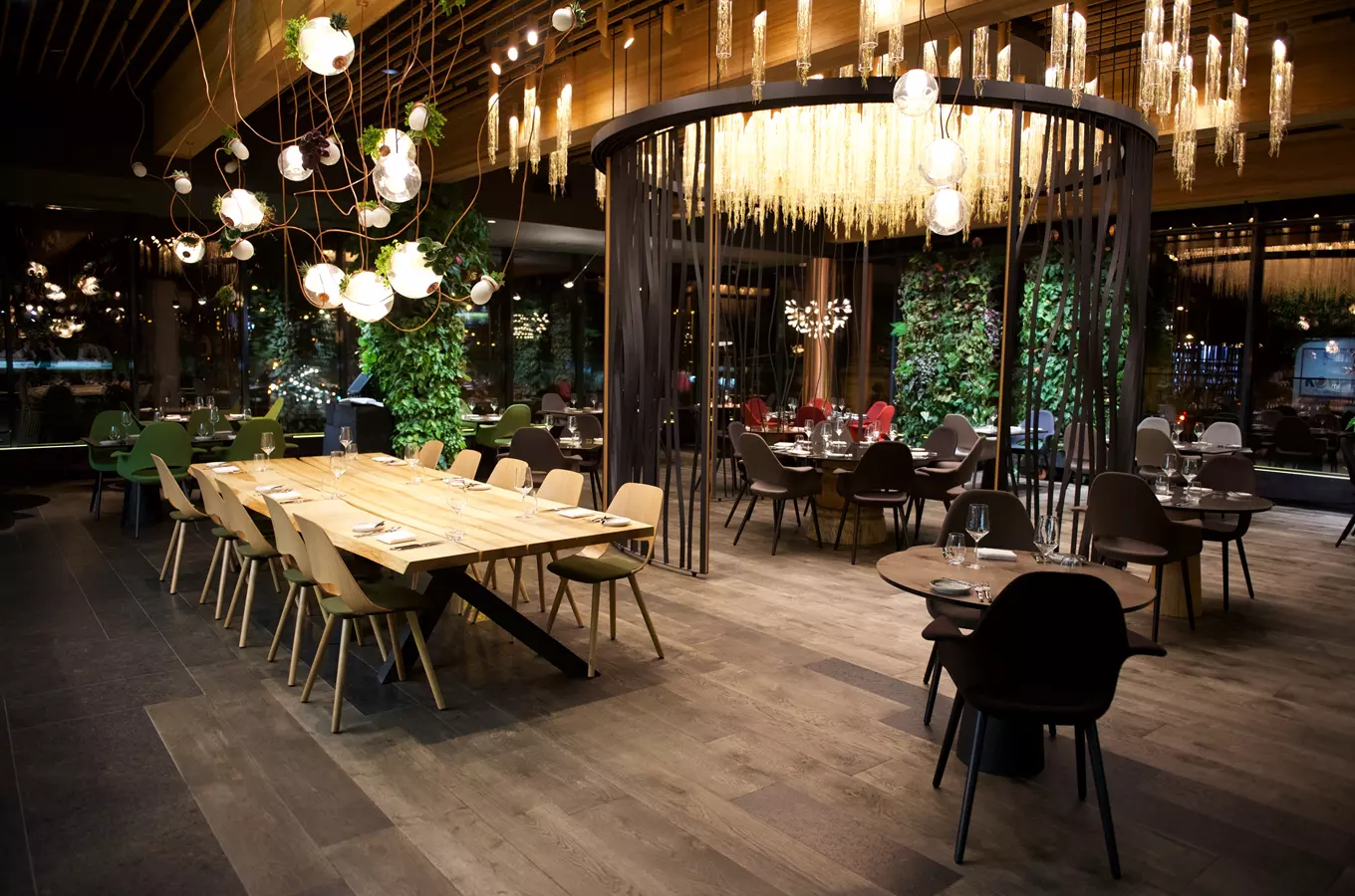 Moderní interiér restaurace s dřevěnými stoly a zelenými prvky.