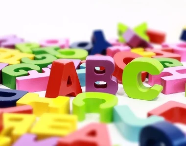 barevné dřevěné písmena ABC rozsypaná na bílém pozadí