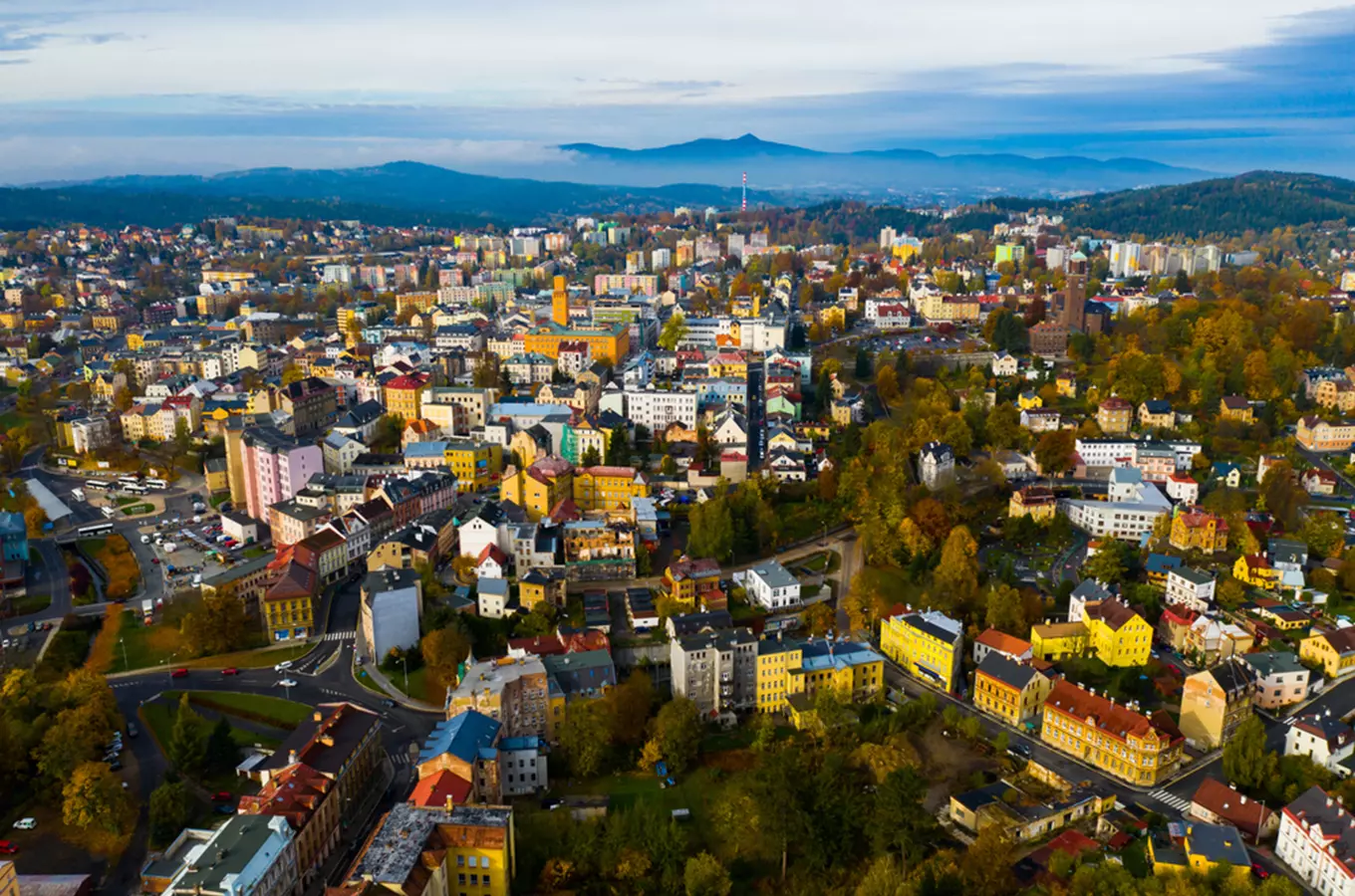 Pohled na město Jablonec nad Nisou s barevnými domy a horami v pozadí.