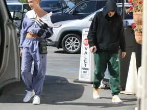 Hailey Bieber chodí venku v modrém oblečení.
