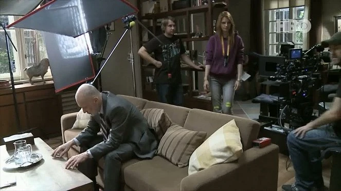 Scéna natáčení s hercem na gauči před kamerou.