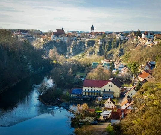 Pohled na město Bechyně v údolí řeky s okolními lesy.