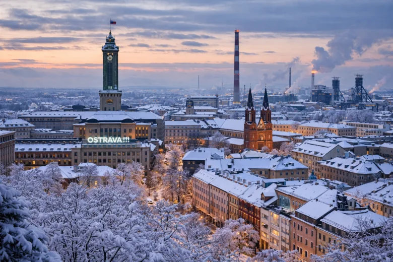 Zasněžená panorama ostravského města s historickými budovami při západu slunce.