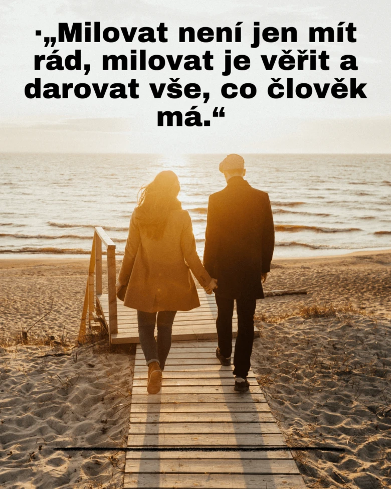 Muž a žena jdou po dřevěné chodníku k moři při západu slunce.