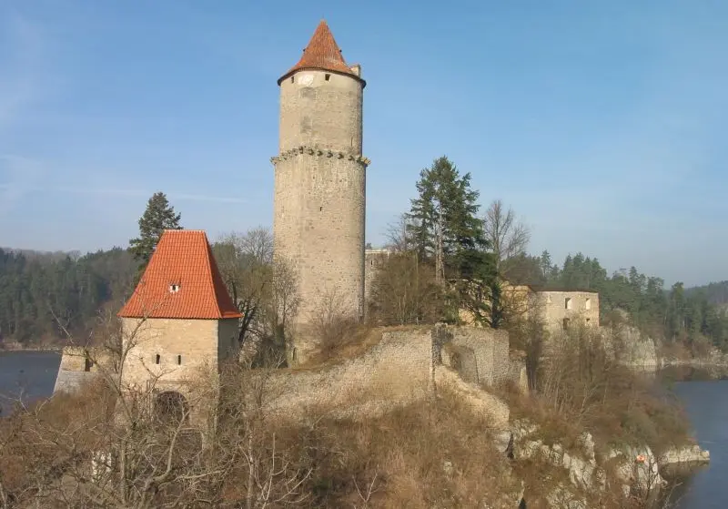 Zámek Zvíkov na vodě s věží a bránou pod modrou oblohou.
