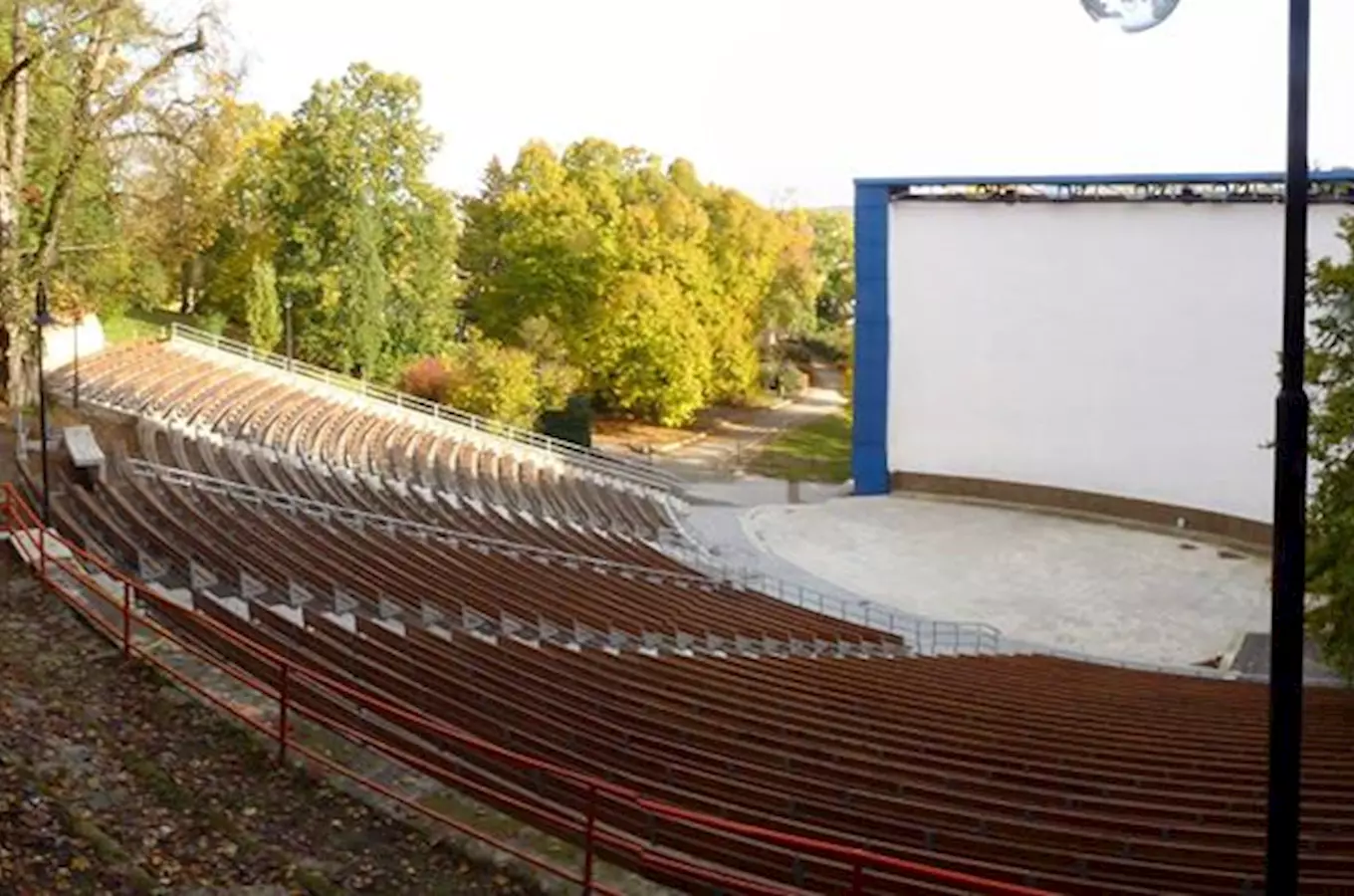 Prázdné letní kino s řadami sedadel před velkou bílou plátnem.