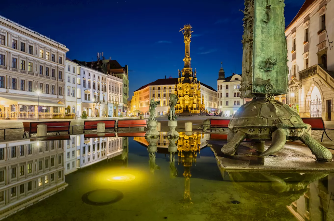 Nocní pohled na náměstí v Olomouci s fontánou a sloupem svaté Marie.