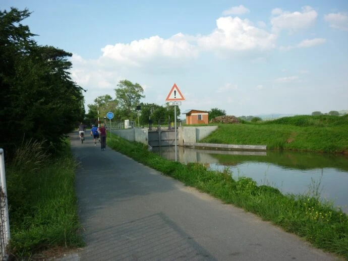 Asfaltová stezka podél kanálu s inline bruslaři.