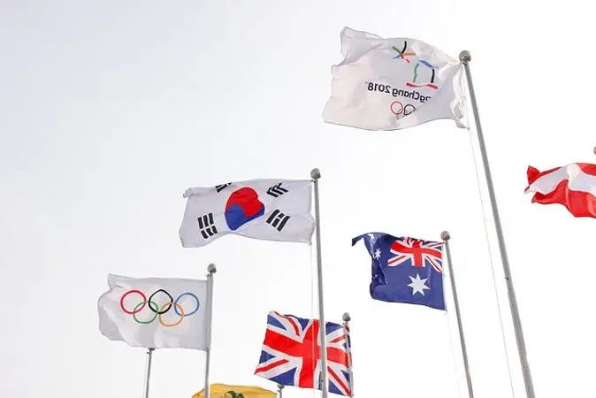 Vlajky olympijských her s vlajkami zemí na sloupech.