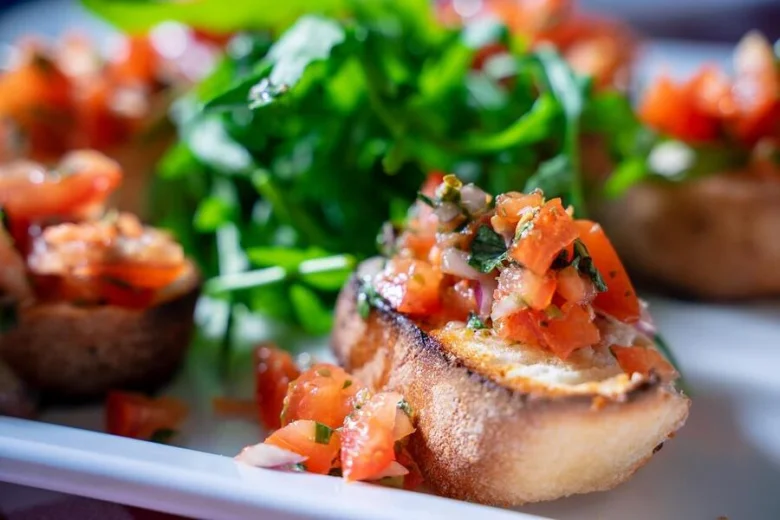 Italská bruschetta s nakrájenými rajčaty a bylinkami na talíři.