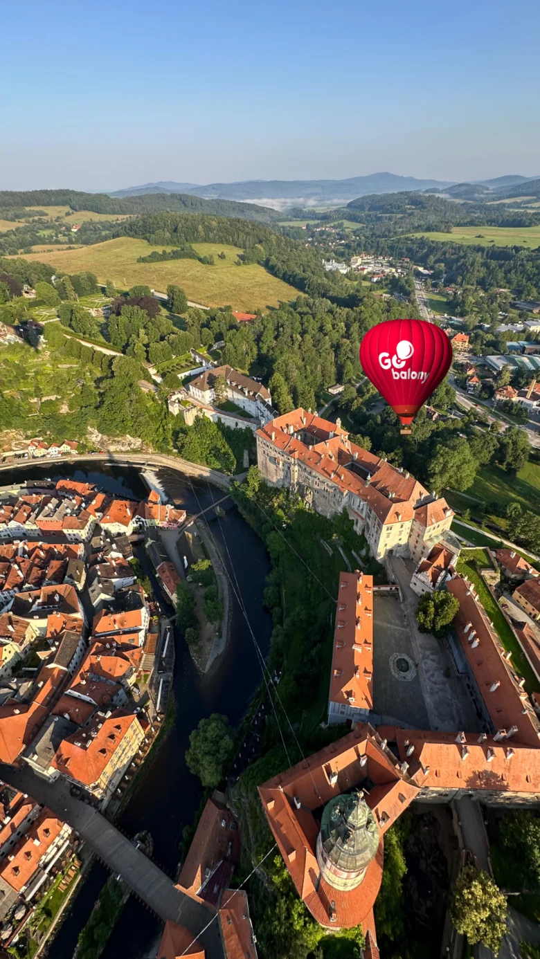 Červený vzducholod nad historickým městem s řekou