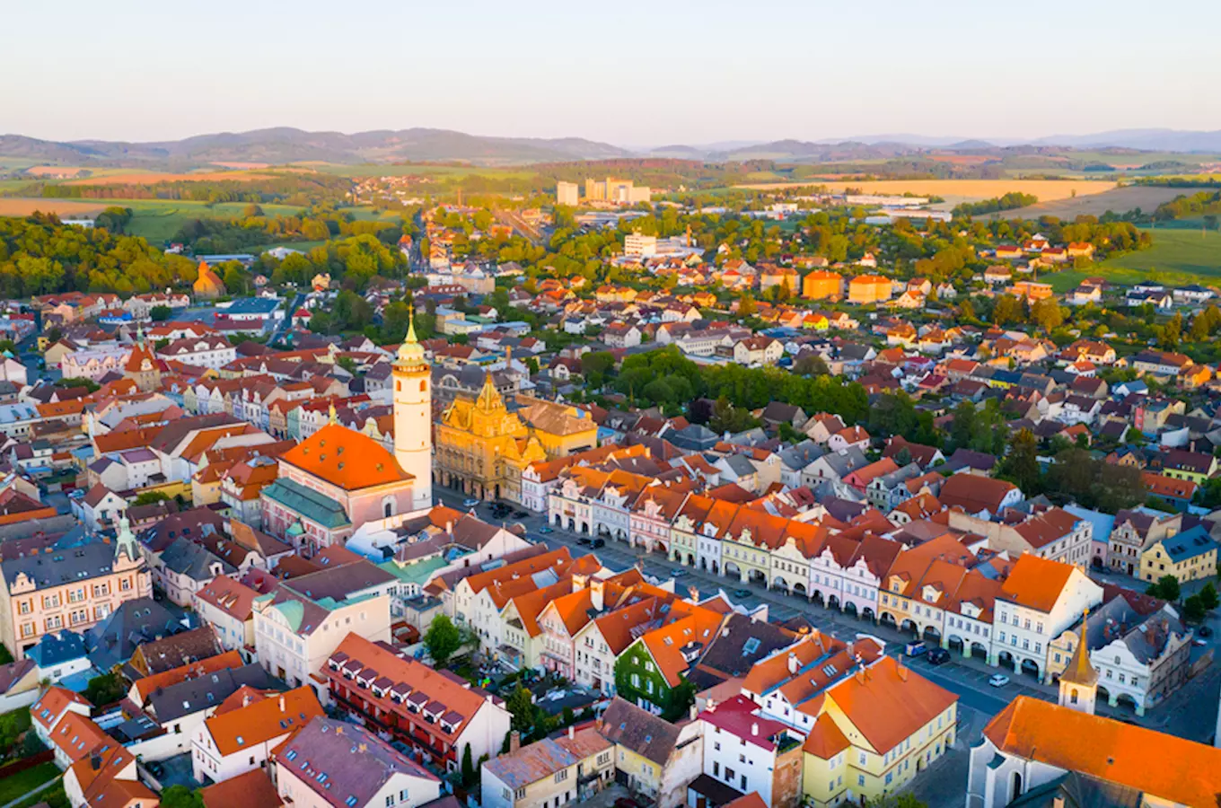 Pohled na město Domažlice s kostelem a okolní krajinou.