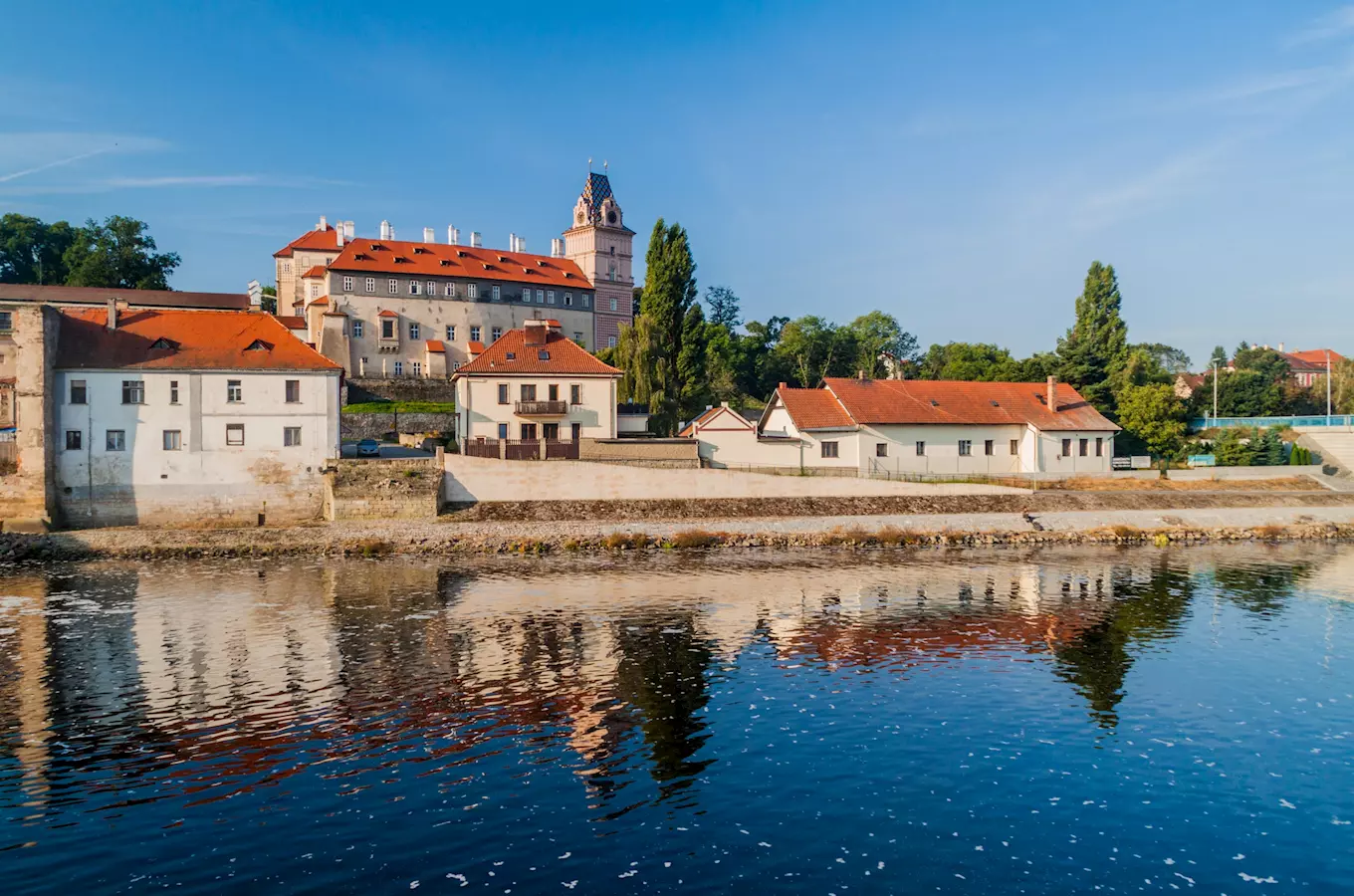 Historické budovy s červenými střechami u řeky v Brandýse nad Labem.