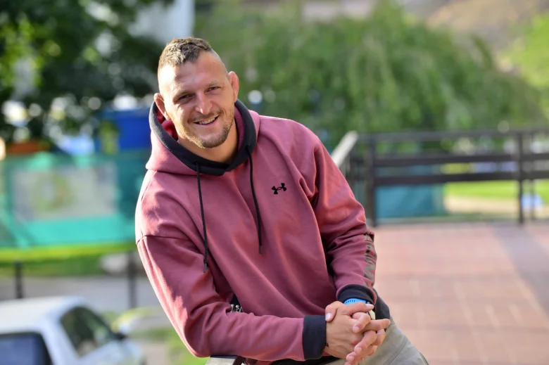 Lukáš Krpálek se usmívá v červené mikině venku.