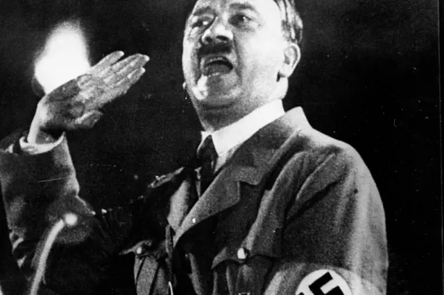 Adolf Hitler s hákovým křížem na rukávu při projevu.