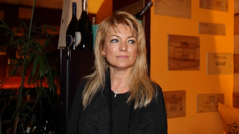 Portrét Evy Vejmělkové v interiéru s vínem na pozadí.