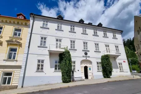 Historická budova lázeňského domu v Mariánských Lázních s bílou fasádou.