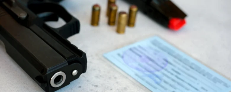 Český zbrojní průkaz s pistolí a náboji na stole.