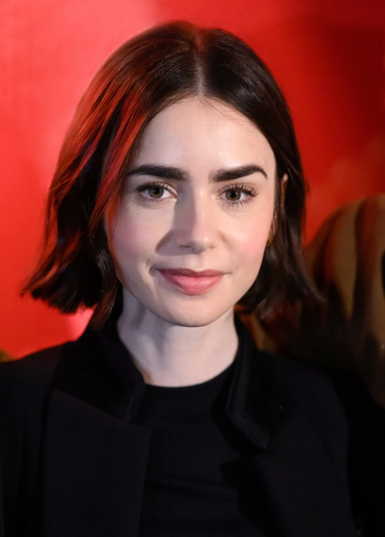 Portrét herečky Lily Collins v černém oblečení na červené pozadí.