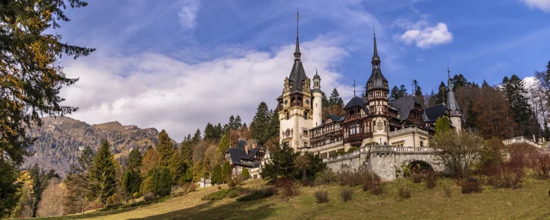 Panoramický pohled na hrad Peleš v Rumunsku mezi horami.