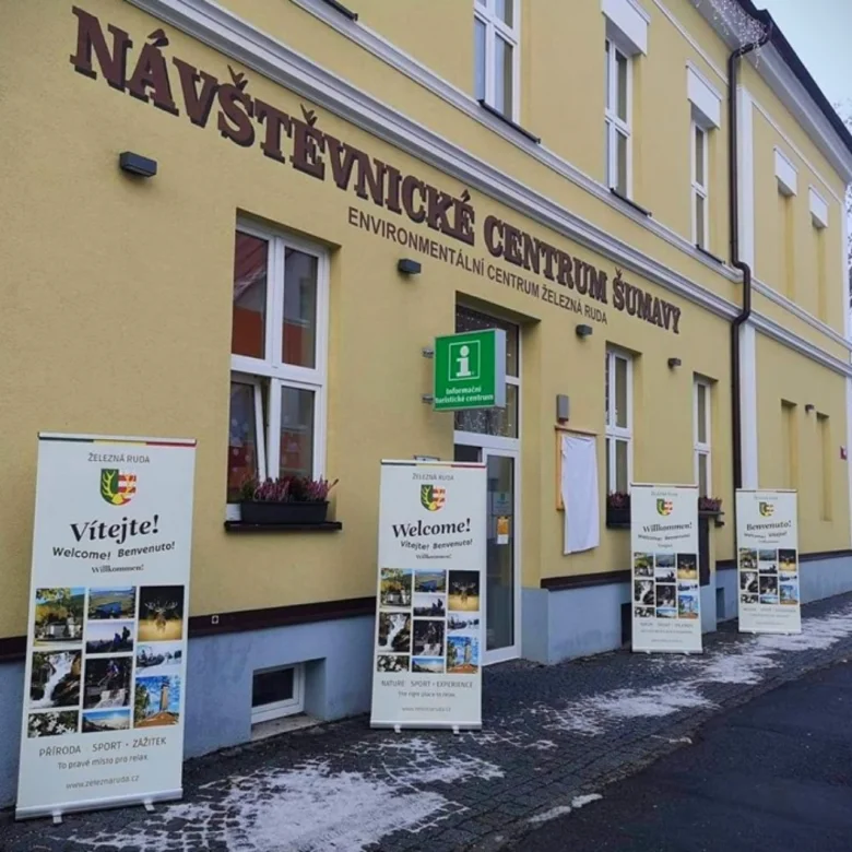 Vstupní budova návštěvnického centra Železná Ruda s reklamními plakáty.
