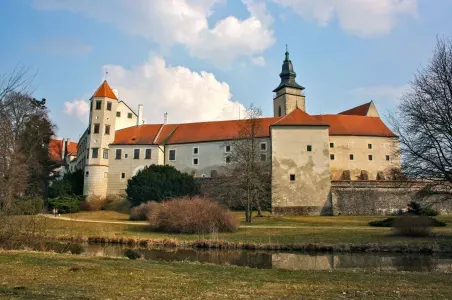 Zámek v Telči s červenou střechou na pozadí modré oblohy.