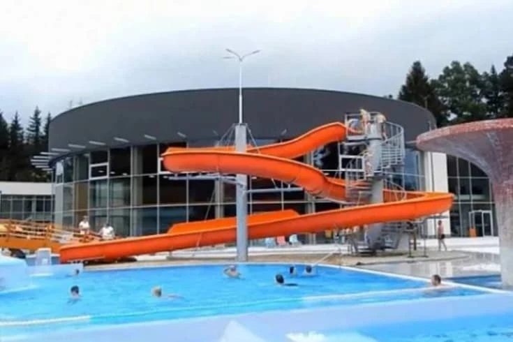 Venkovní aquapark s oranžovými skluzavkami do bazénu v Šumperku.