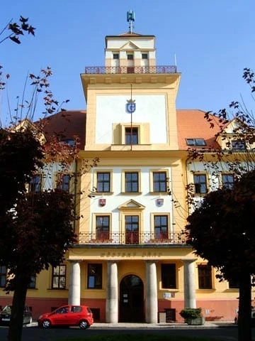 Zámek v Krasicích s červeným autem před budovou.