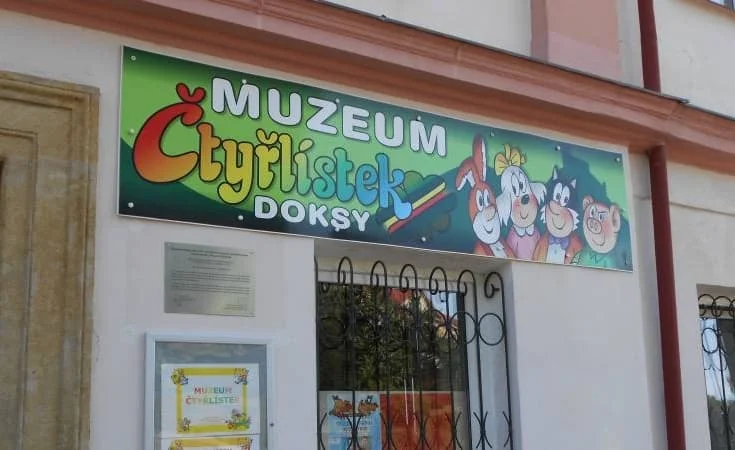 Vývěska muzea Čtyřlistek v Doksách s barevnými postavami.