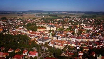 Pohled na město Louny s červenými střechami a okolní poli.