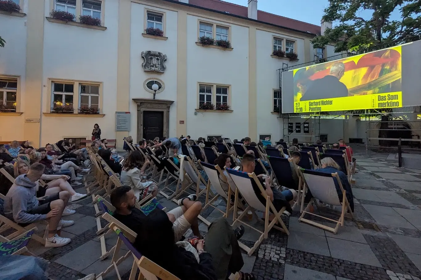 Venkovní kino s diváky na lehátkách před projekcí v Brně.