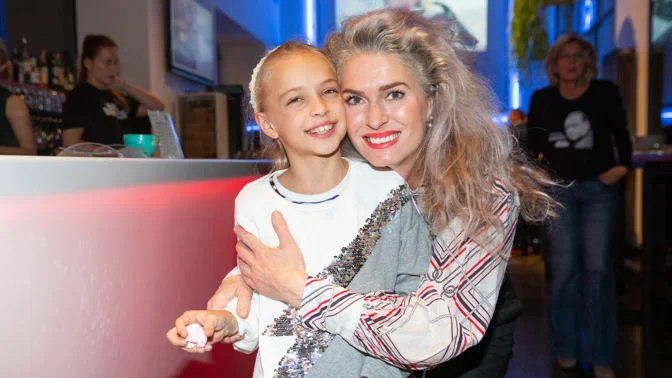 Žena objímá mladou dívku na společenské akci.