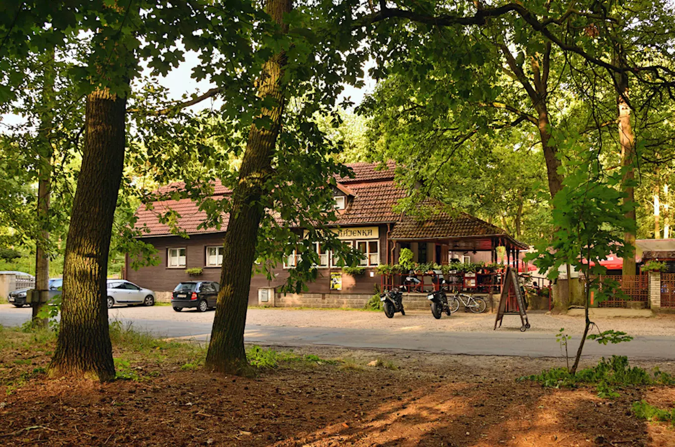 Dřevěná budova v lese s restaurací Kersko Hájenka.