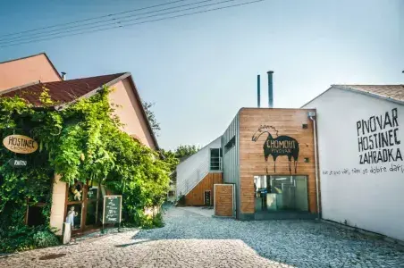 Exteriér pivovaru s dřevěnou fasádou a zelení v Olomouci.