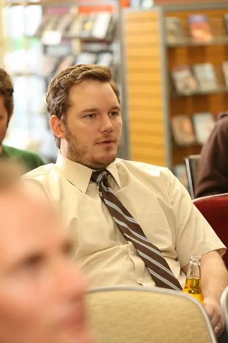 Chris Pratt sedící v knihkupectví s lahví