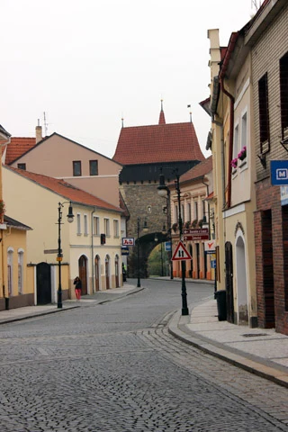 Historická ulice v Lounech s gotickou branou a starobylými domy.