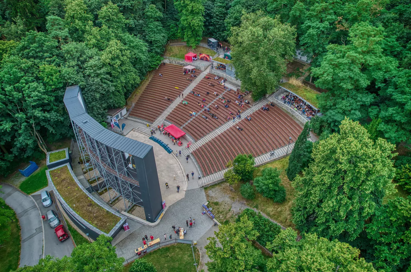 Letní kino v lese s divadlem na otevřeném prostranství.
