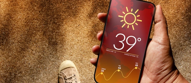 Ruka drží chytrý telefon s aplikací pro počasí.