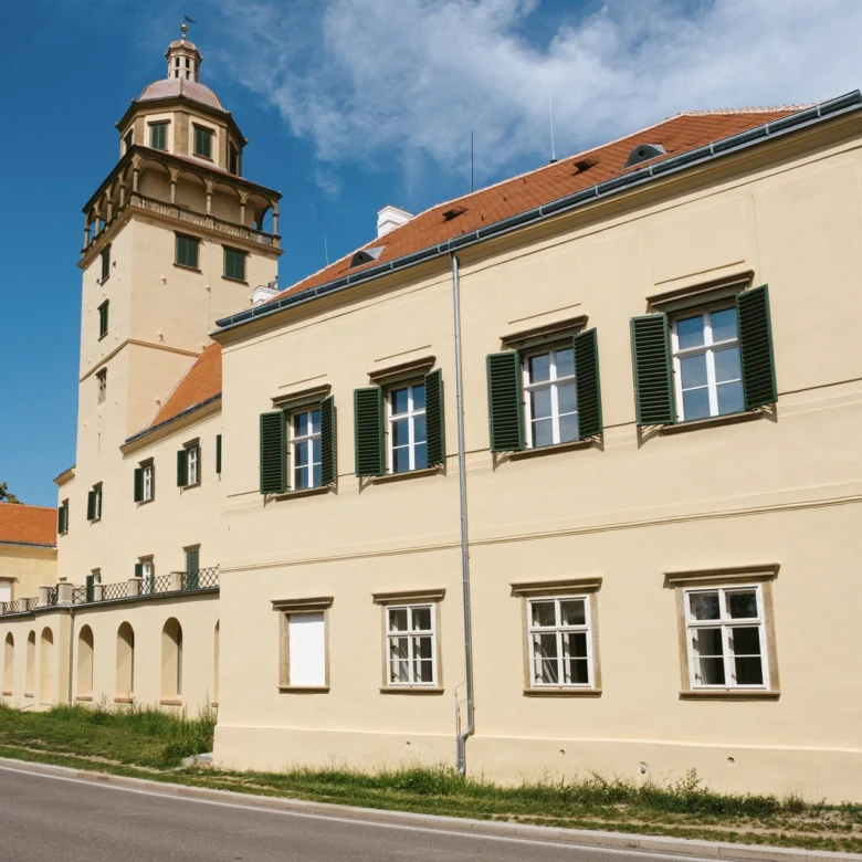 Zámek v Moravském Krumlově s věží a okny pod modrou oblohou.