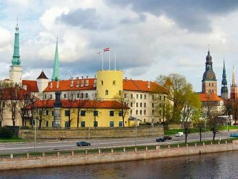 Pohled na historické střechy a věže starého města Rigy u řeky.