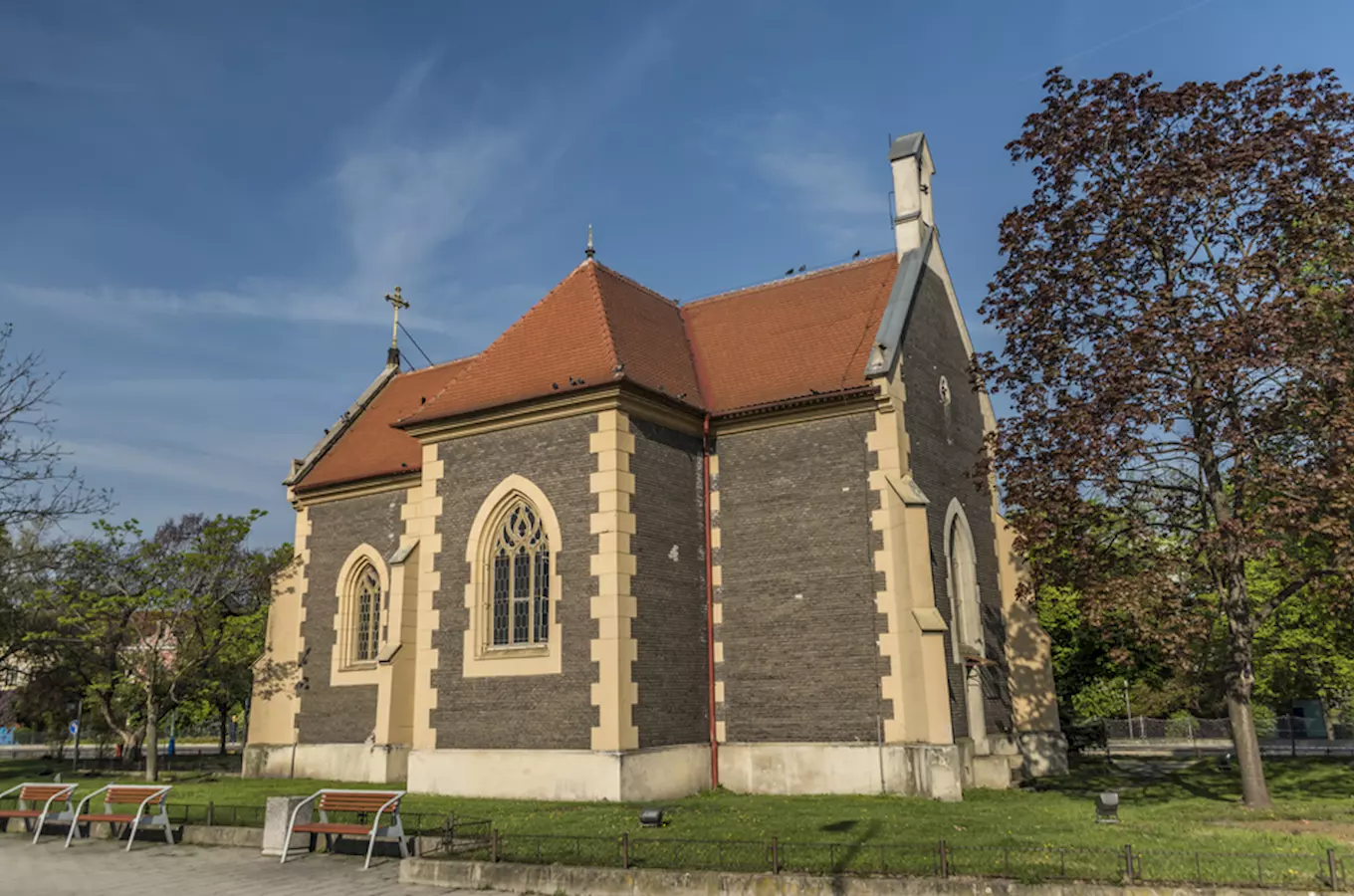 Historická kostel v Břeclavi s červenou střechou uprostřed zeleného parku.