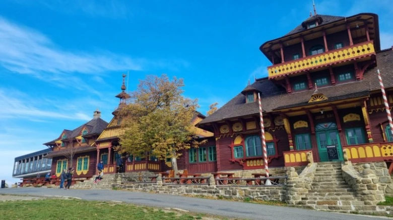 Tradiční dřevěné stavby na Beskydech pod modrou oblohou.