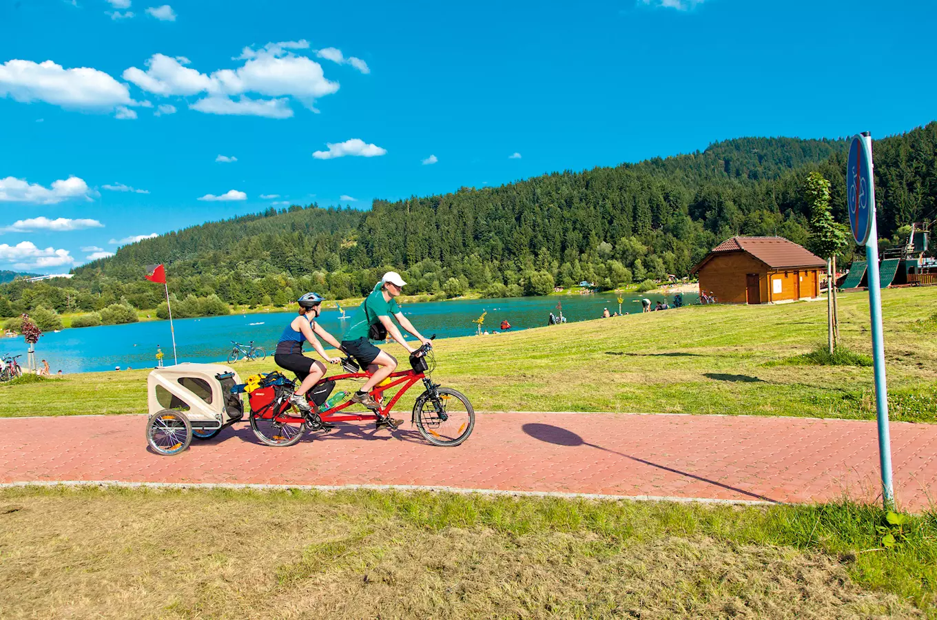 Dva cyklisté na dvojkolejku s přívěsem u jezera v Beskydech