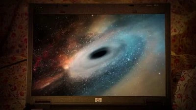 Laptop zobrazující černou díru obklopenou galaxií ve vesmíru.