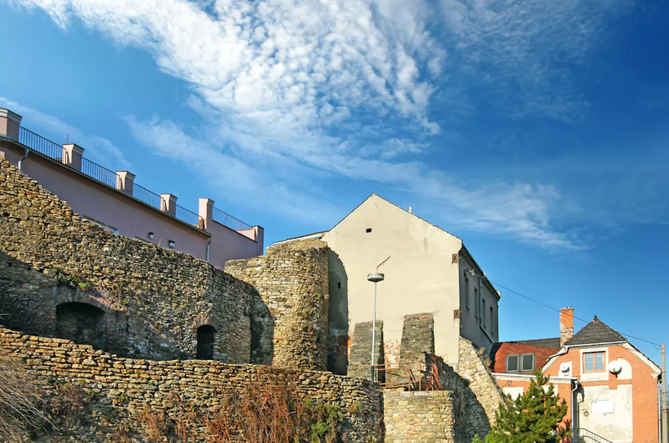 Staré kamenné zdi hradu v Přerově s domy pod modrou oblohou.